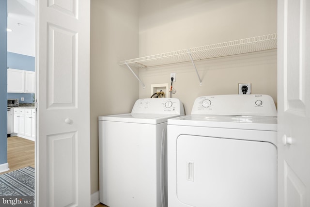 clothes washing area featuring light wood-type flooring, laundry area, washing machine and dryer, and a toaster