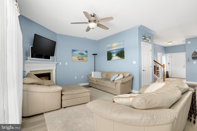 living area with stairway, wood finished floors, a ceiling fan, and baseboards