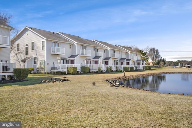 rear view of house with a water view, a residential view, and a yard