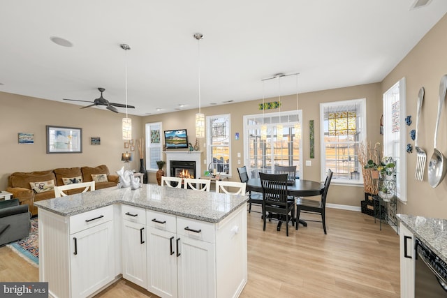 kitchen featuring white cabinetry, hanging light fixtures, light stone countertops, and dishwasher