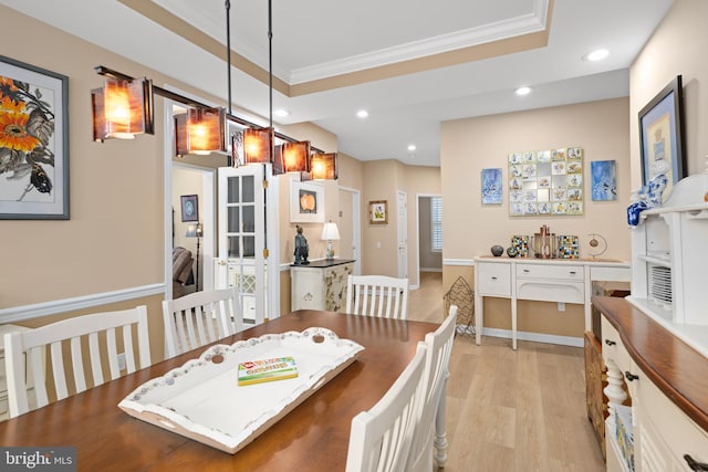 dining area featuring a tray ceiling, ornamental molding, and light hardwood / wood-style floors