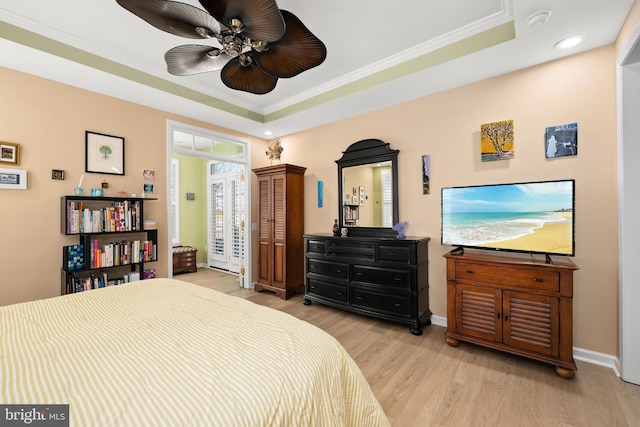 bedroom with crown molding, a tray ceiling, light hardwood / wood-style floors, and ceiling fan