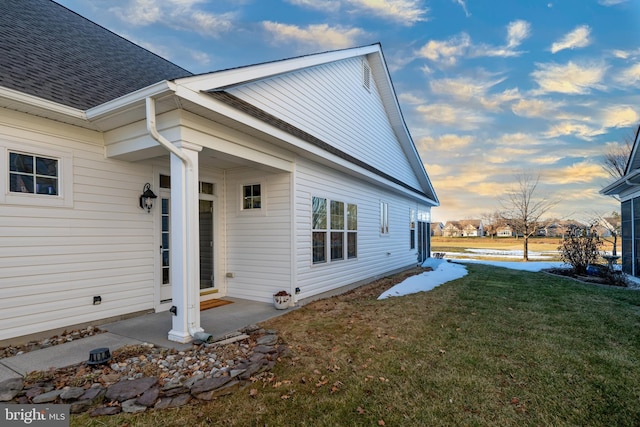 property exterior at dusk featuring a yard