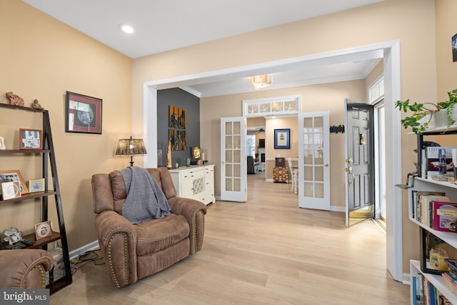 living area with crown molding, light hardwood / wood-style flooring, and french doors