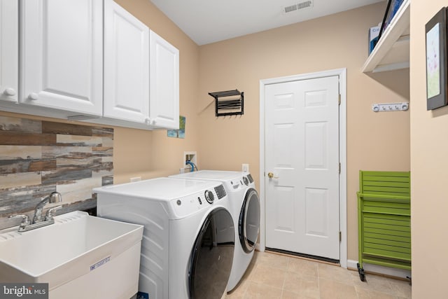 clothes washing area featuring sink, light tile patterned floors, washer and clothes dryer, and cabinets