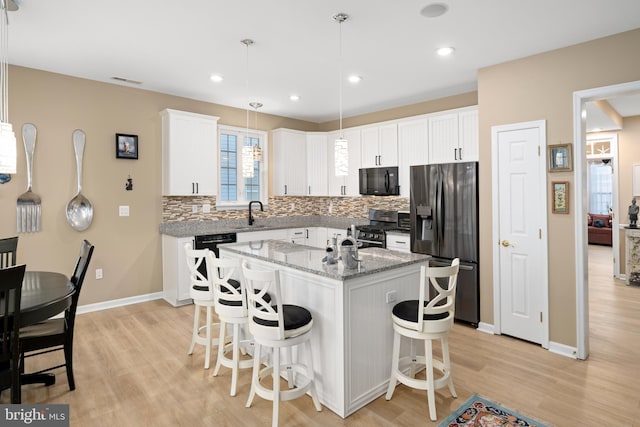 kitchen with white cabinetry, a center island, hanging light fixtures, and black appliances