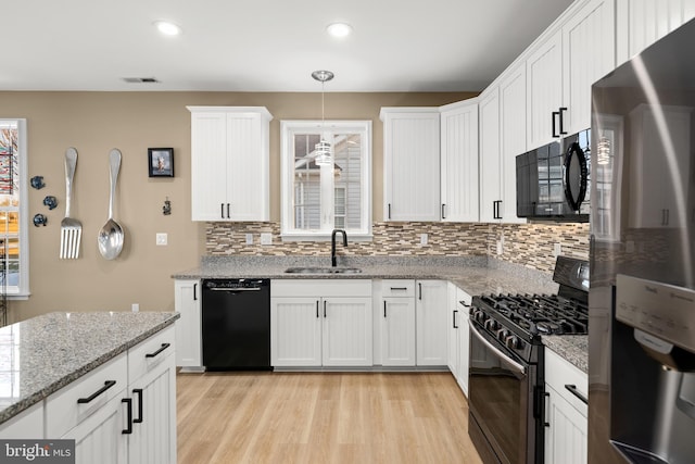 kitchen featuring sink, white cabinetry, hanging light fixtures, black appliances, and light stone countertops