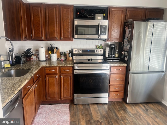 kitchen with light stone counters, sink, dark hardwood / wood-style flooring, and appliances with stainless steel finishes