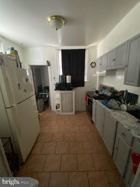 kitchen featuring stainless steel electric stove, light stone countertops, and white fridge