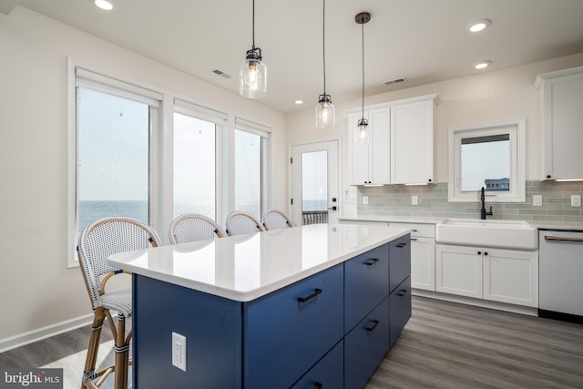 kitchen featuring a kitchen island, decorative light fixtures, white cabinetry, dishwasher, and sink