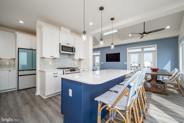 kitchen with a kitchen island, range with gas cooktop, decorative light fixtures, white cabinetry, and fridge