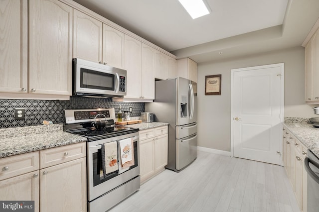 kitchen featuring stainless steel appliances, light stone countertops, and backsplash