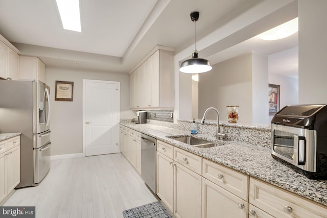 kitchen featuring sink, light wood-type flooring, pendant lighting, stainless steel appliances, and light stone countertops