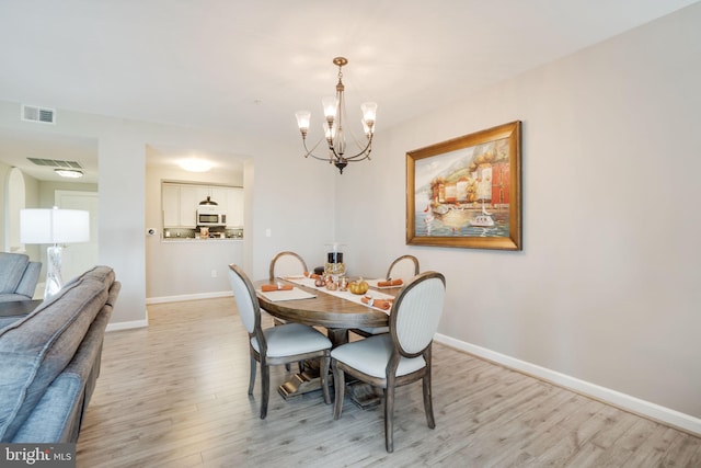 dining area featuring light hardwood / wood-style flooring and a notable chandelier