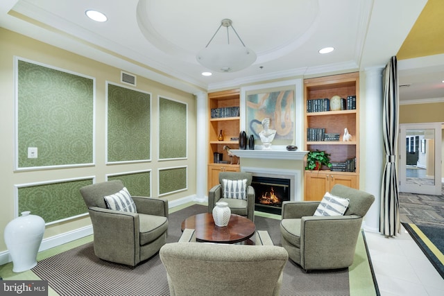 sitting room featuring built in shelves, ornamental molding, and a tray ceiling