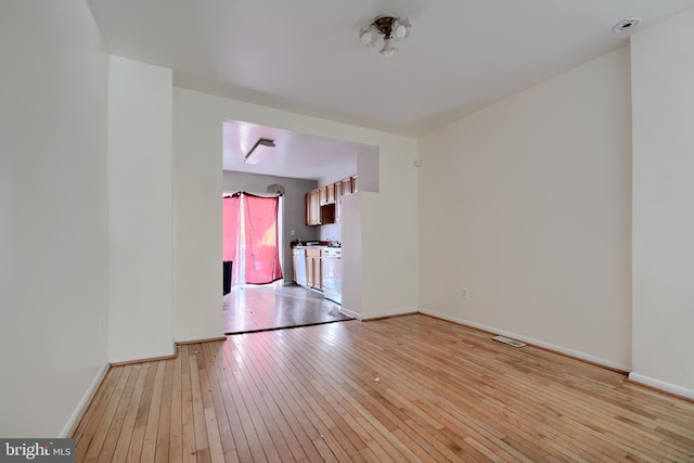 spare room with light wood-style floors, visible vents, and baseboards