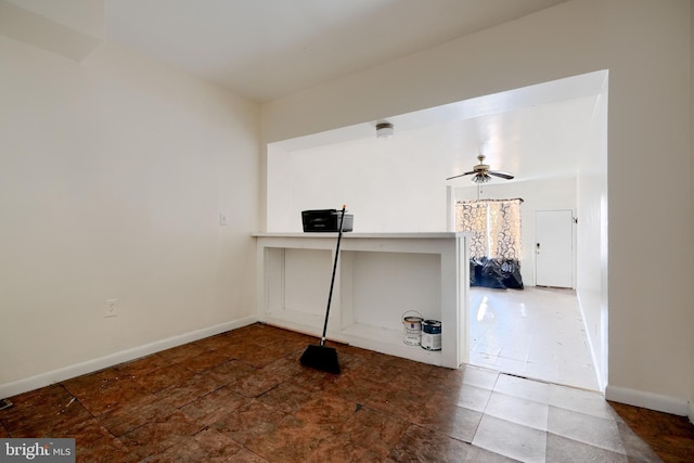 unfurnished office with a ceiling fan and baseboards