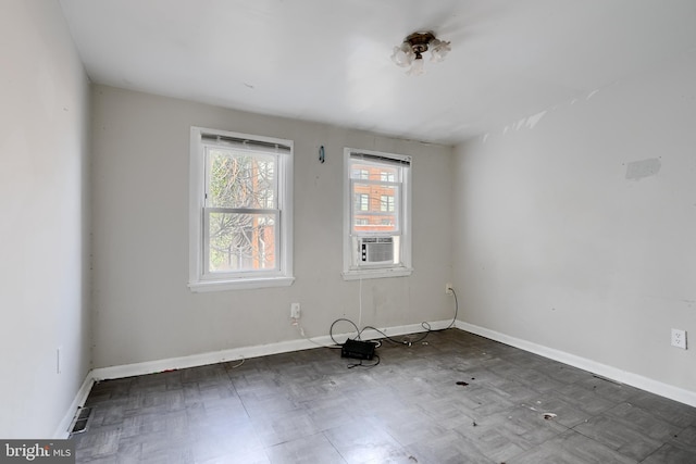 empty room with cooling unit, visible vents, baseboards, and dark floors