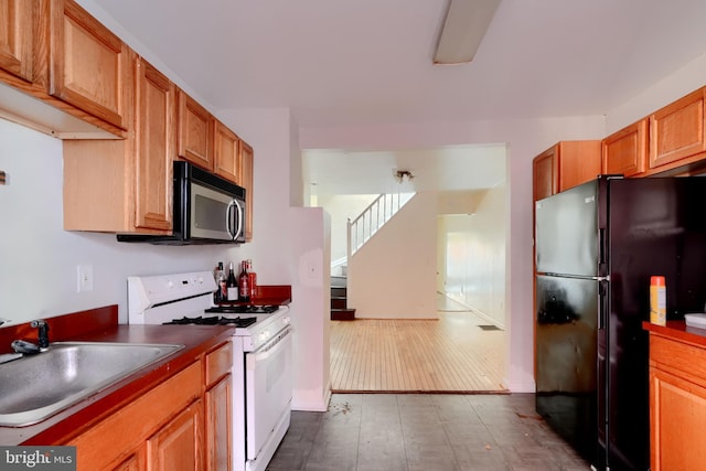 kitchen featuring dark countertops, stainless steel microwave, freestanding refrigerator, a sink, and white gas range oven