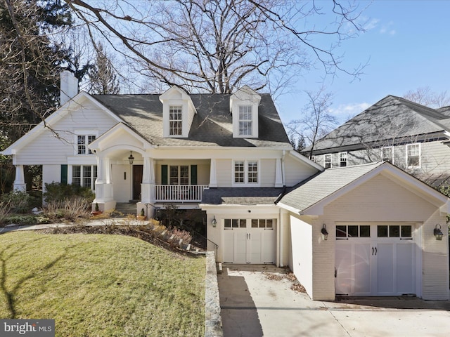 view of front of property featuring roof with shingles, covered porch, a front lawn, concrete driveway, and brick siding