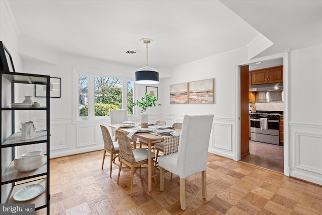 dining space featuring ornamental molding and light parquet floors