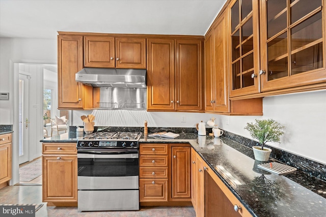 kitchen with dark stone countertops, extractor fan, and stainless steel gas range oven