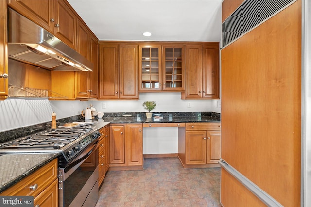 kitchen featuring gas stove, paneled refrigerator, and dark stone counters