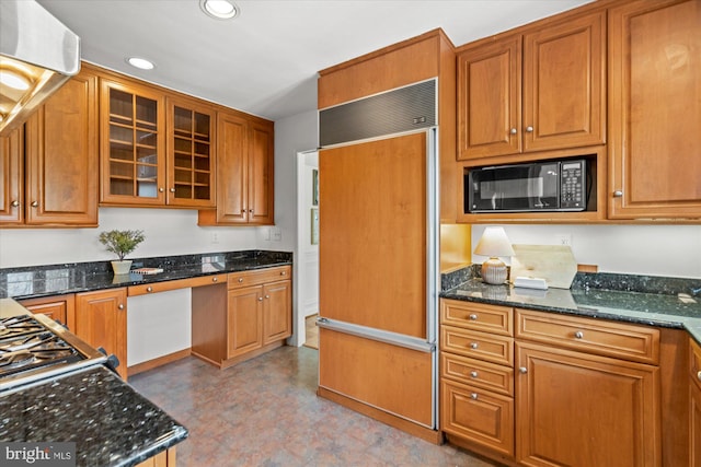 kitchen featuring built in appliances, built in desk, dark stone countertops, and ventilation hood