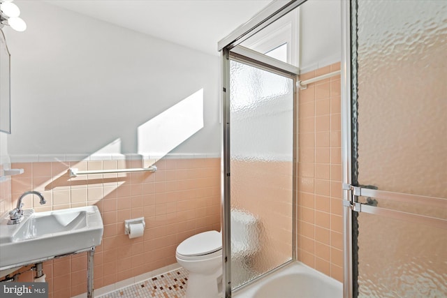 full bathroom with bath / shower combo with glass door, sink, tile walls, toilet, and tile patterned floors