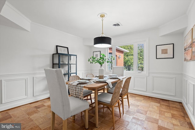 dining space featuring ornamental molding and light parquet floors