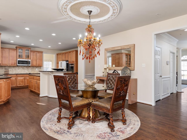 dining area with decorative columns, ornamental molding, dark hardwood / wood-style floors, and an inviting chandelier