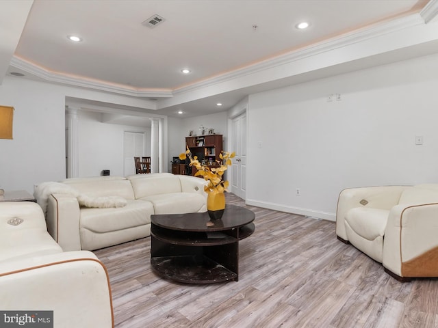 living room with a tray ceiling, ornamental molding, ornate columns, and light wood-type flooring