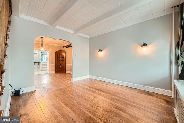 spare room with beam ceiling and light hardwood / wood-style floors