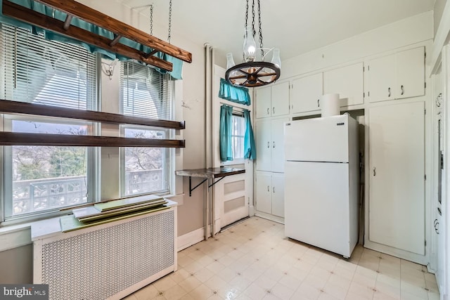 kitchen with pendant lighting, white cabinetry, radiator heating unit, a chandelier, and white fridge