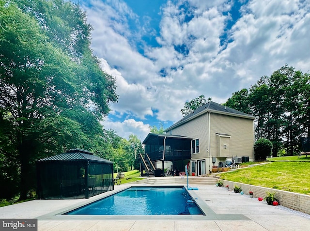 view of pool featuring a lawn, a gazebo, a patio, a sunroom, and central air condition unit