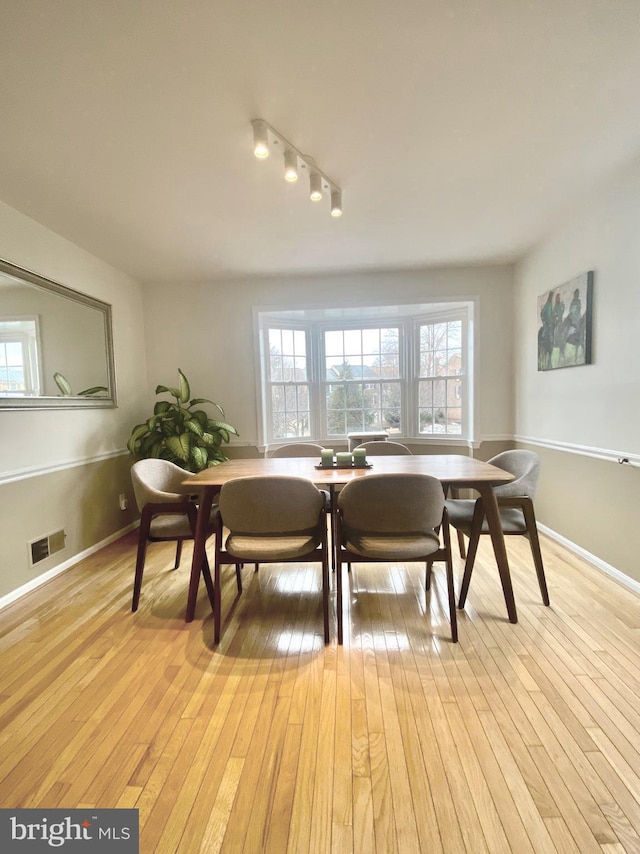 dining space featuring light wood-style floors, visible vents, and baseboards