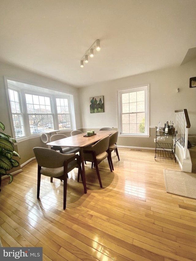 dining room featuring baseboards, visible vents, and light wood finished floors