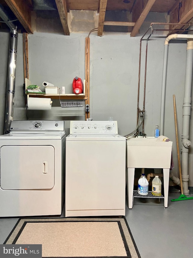 laundry area with laundry area, a sink, and washing machine and clothes dryer