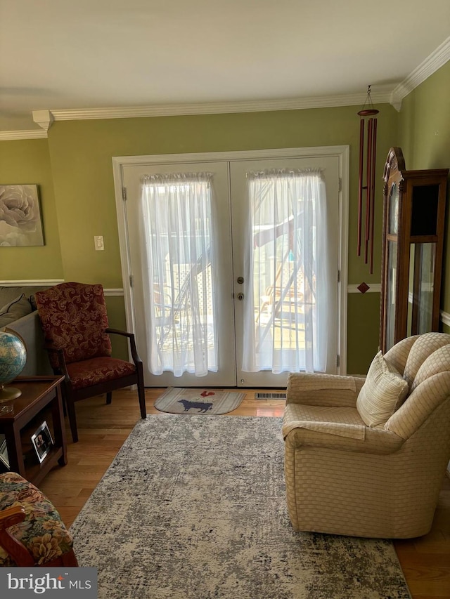 living room with crown molding, wood-type flooring, and french doors