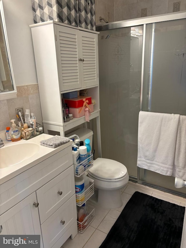 bathroom featuring tile patterned flooring, vanity, toilet, and walk in shower