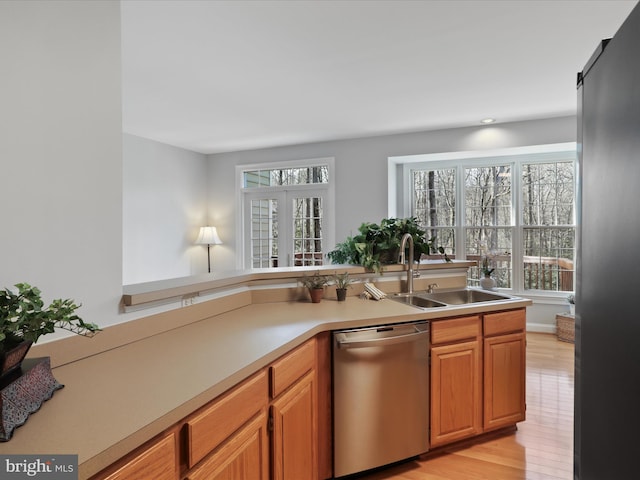 kitchen with stainless steel appliances, sink, and light hardwood / wood-style flooring