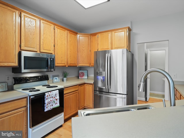 kitchen with appliances with stainless steel finishes and light hardwood / wood-style floors