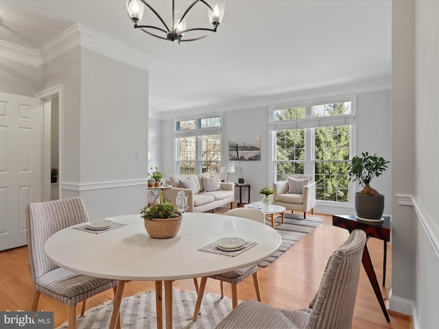 dining space with crown molding, a notable chandelier, and light wood-type flooring