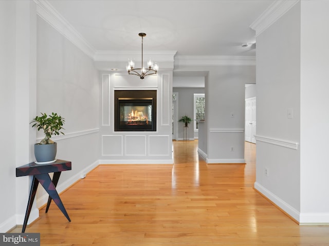 foyer featuring crown molding, a multi sided fireplace, wood-type flooring, and an inviting chandelier