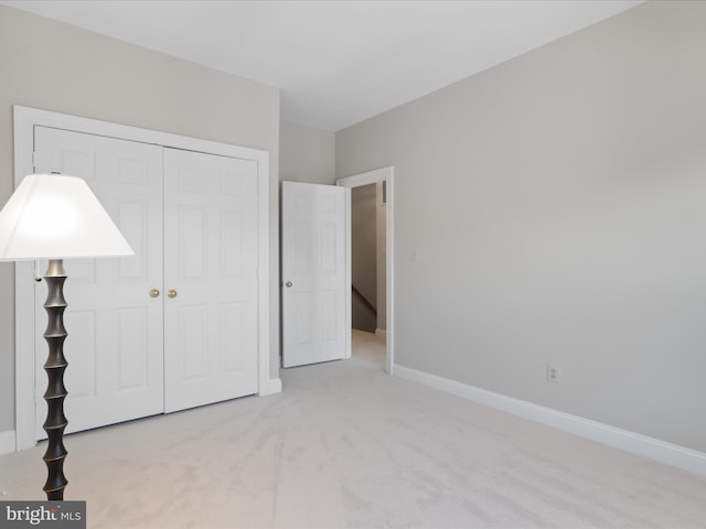 unfurnished bedroom with light carpet and a closet