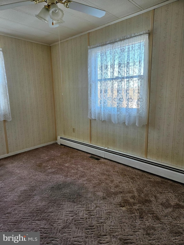 carpeted spare room with a baseboard radiator and ceiling fan