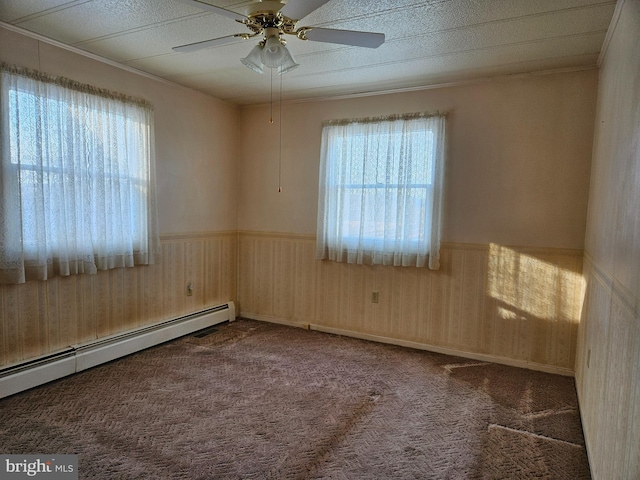 carpeted spare room featuring a healthy amount of sunlight, a baseboard heating unit, and ceiling fan