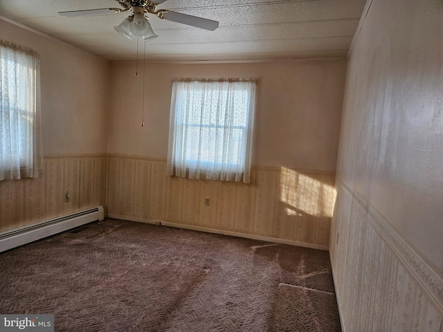 spare room with a baseboard radiator, ceiling fan, and dark carpet