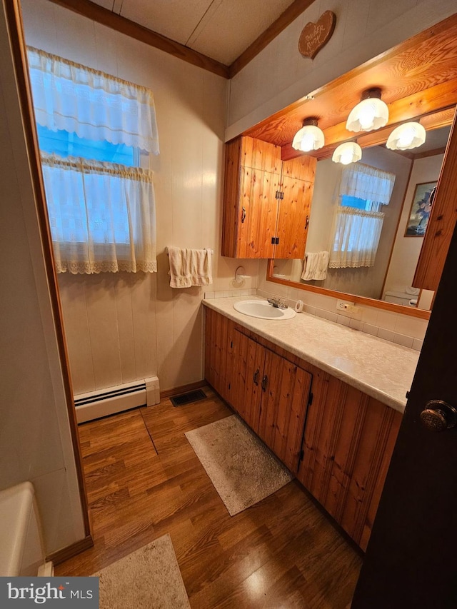 bathroom featuring a baseboard radiator, wood-type flooring, a wealth of natural light, and ornamental molding