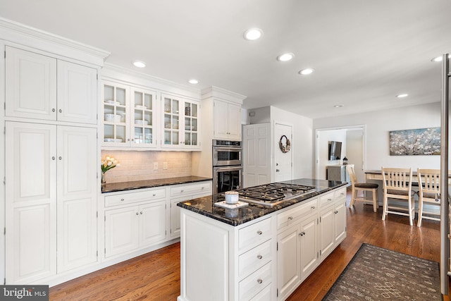 kitchen with white cabinetry, dark stone countertops, appliances with stainless steel finishes, dark hardwood / wood-style flooring, and backsplash